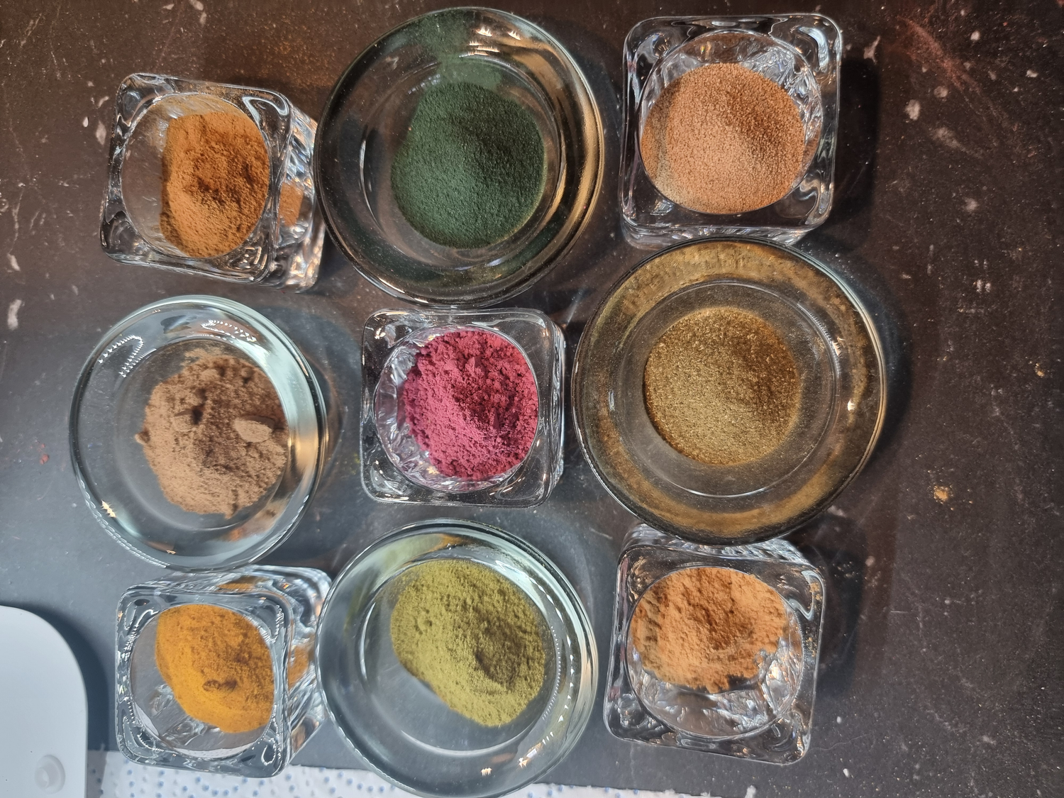 Exfoliating natural ingredients like Rosehip powder and ground walnut shell in glass pots. Different shades of green, light brown and yellow to orange.