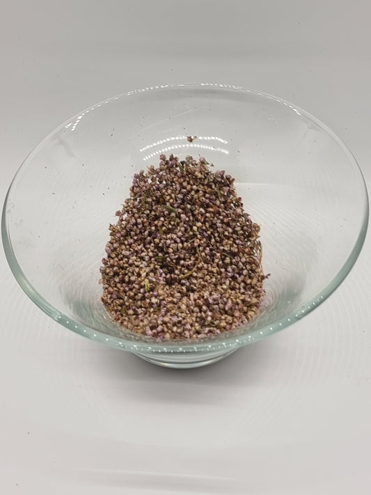 a glass bowl containing dried small heather flowers. Tiny round light purple coloured flowers are mixed with tiny bits of green from the plant