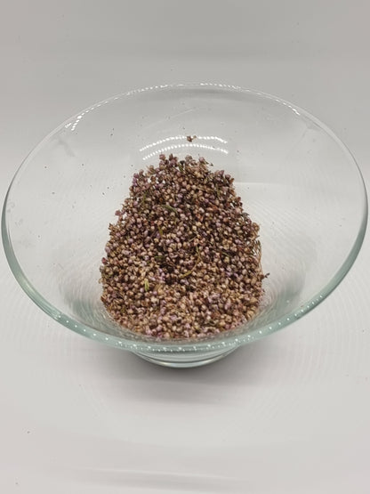 a glass bowl containing dried small heather flowers. Tiny round light purple coloured flowers are mixed with tiny bits of green from the plant