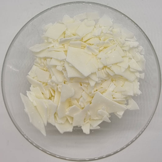 glass bowl containing thin irregular shaped flakes of soy wax for cosmetic and candle use. They are white to cream in colour and range in size from the size of your little finger nail to the size of your whole thumb.