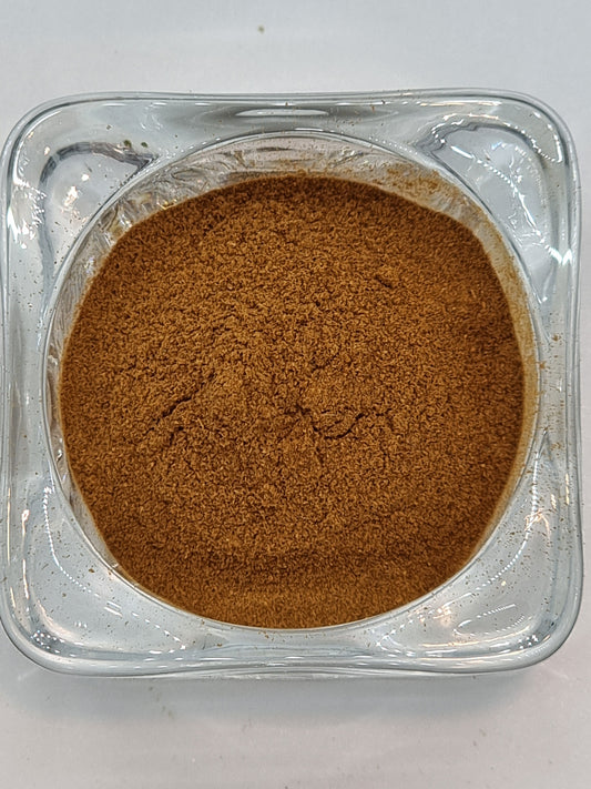 a glass bowl containing dry finely ground cinnamon powder that has a deep orange to brown colour. Some texture can be seen with very small particles visible