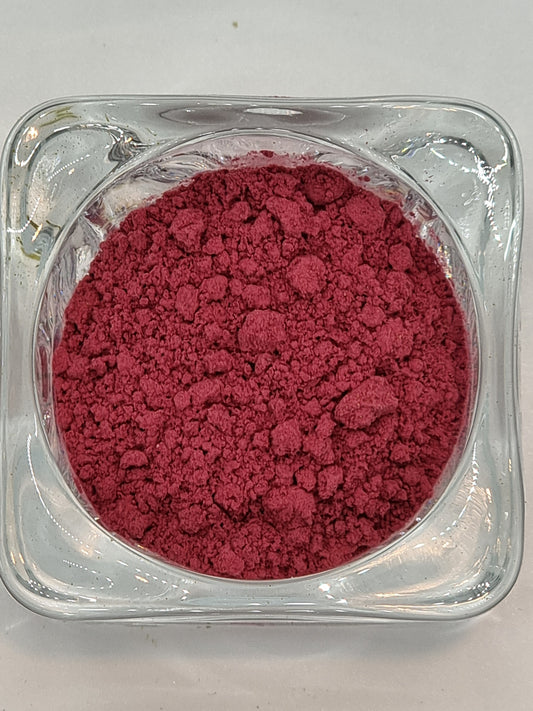 gass bowl containing finely ground hibiscus flower powder which is a deep pink red