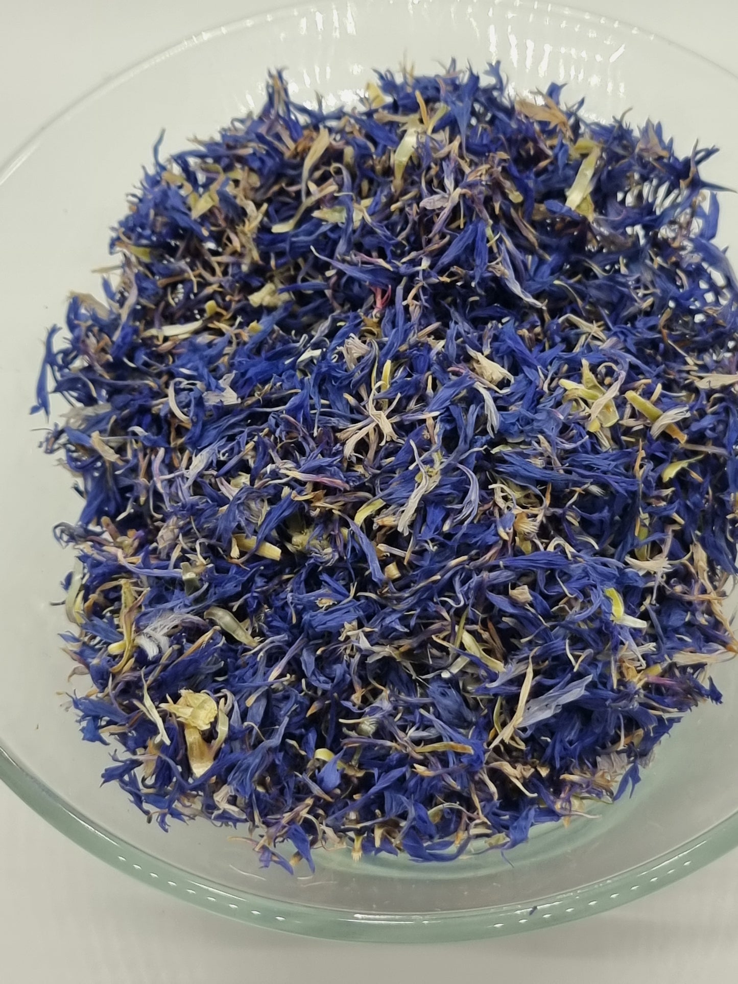 a glass bowl containing lots of small bright blue cornflower petals